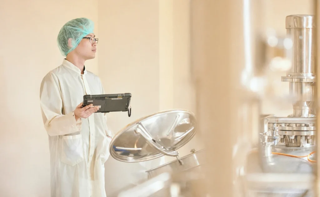 KH Roberts staff in protective clothing and hair net holding a tablet, overseeing the production process.